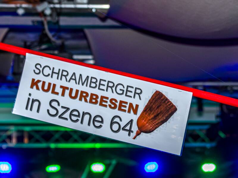 Besen hängt an der Decke, im Hintergrund spielt eine Queen Tribute Band